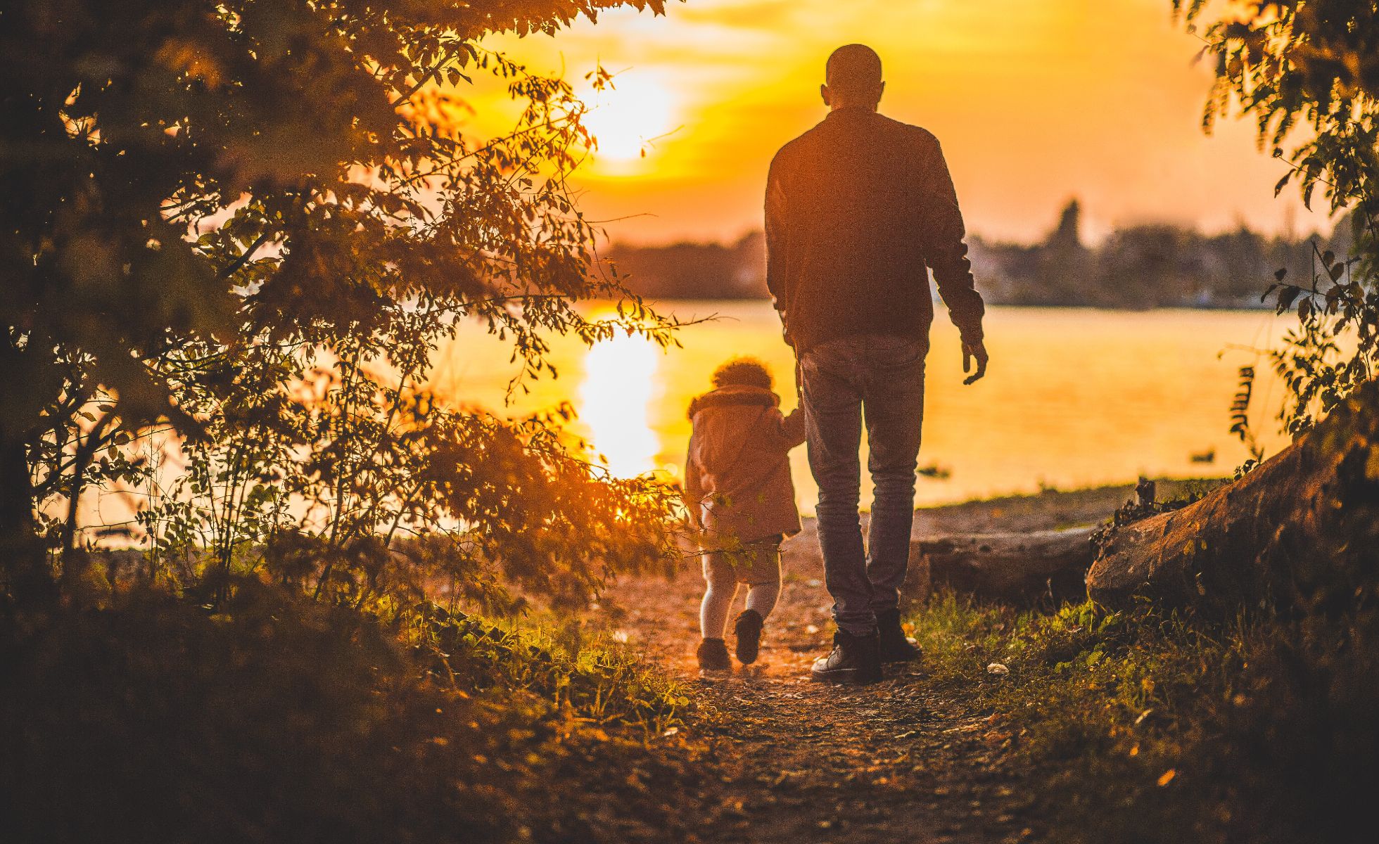 Father and daughter following pathway in sunset